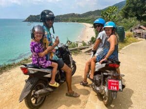 Family riding scooters in Thailand
