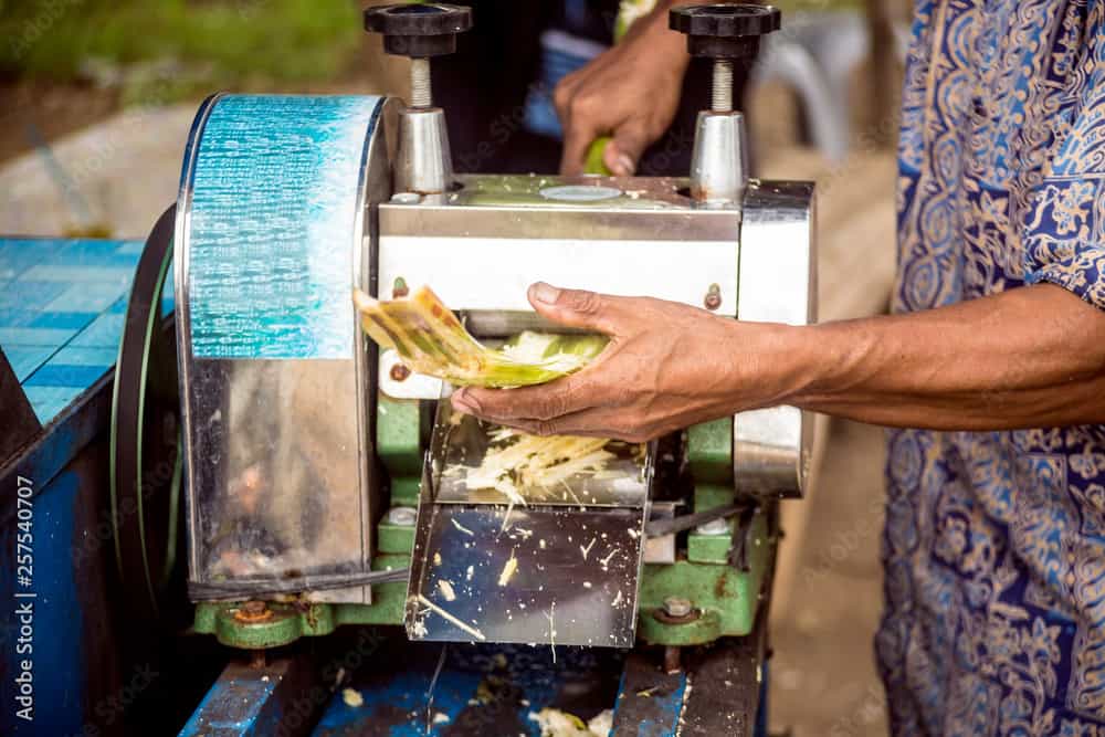 A Man Uses A Machine To Squeeze Sugar Cane Juice Out In Java, Indonesia