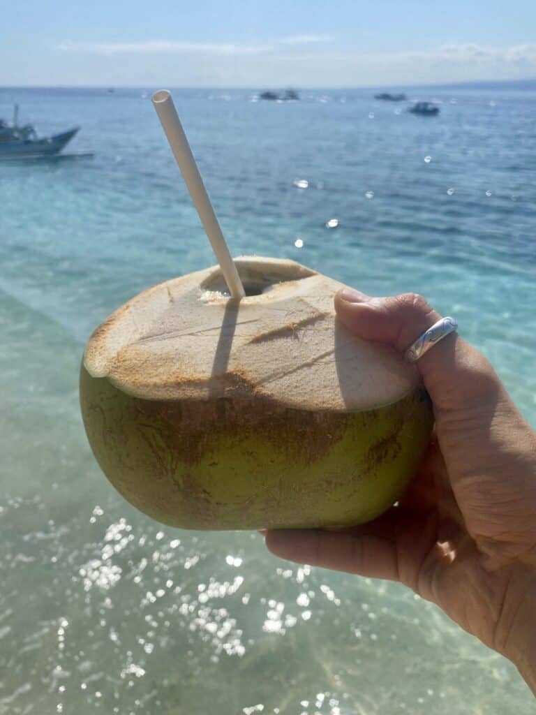 Holding a coconut by the blue sea