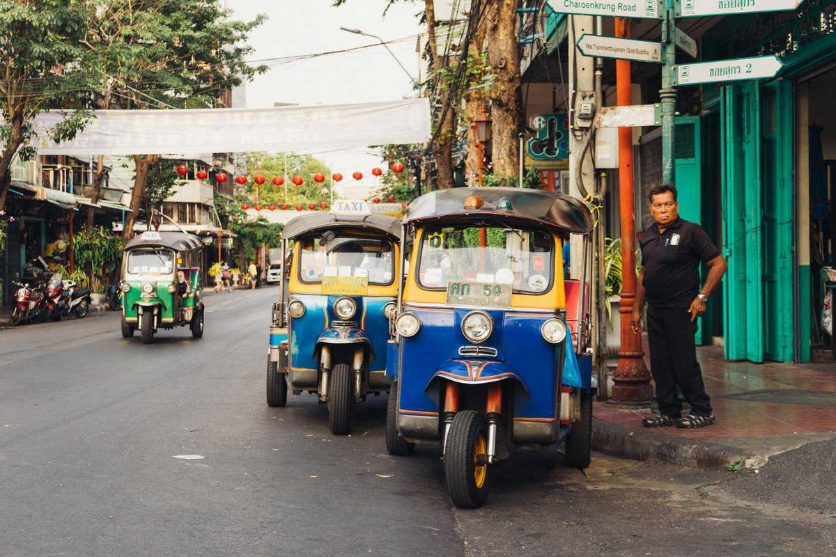 Man Standing Beside Parked TukTuks in Bangkok